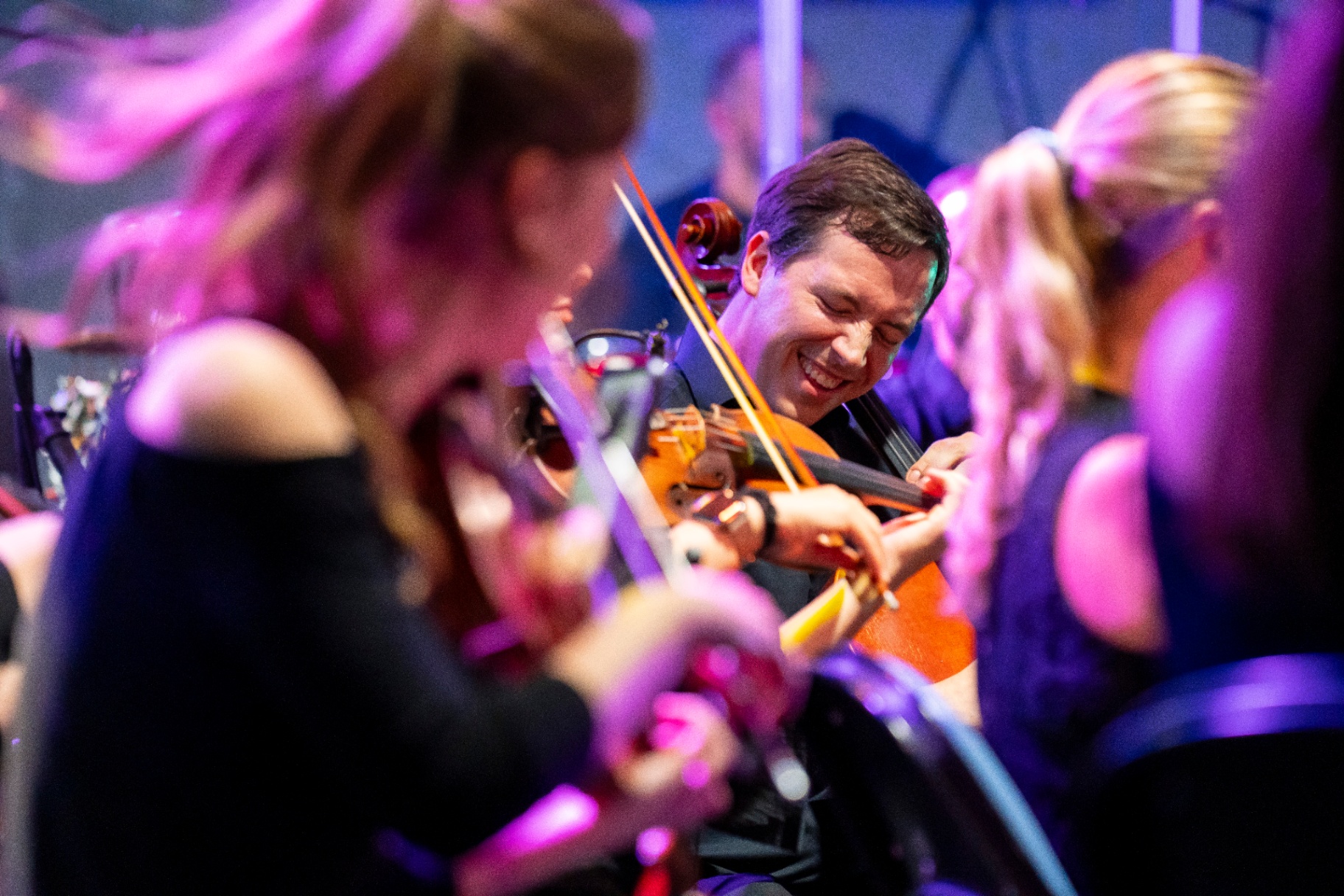 Nu Deco Ensemble cellist smiling mid-performance during the Ledisi concert