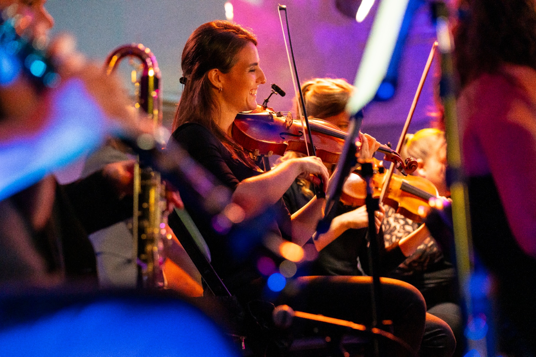 Nu Deco Ensemble violinist smiling mid-performance during the Ledisi concert